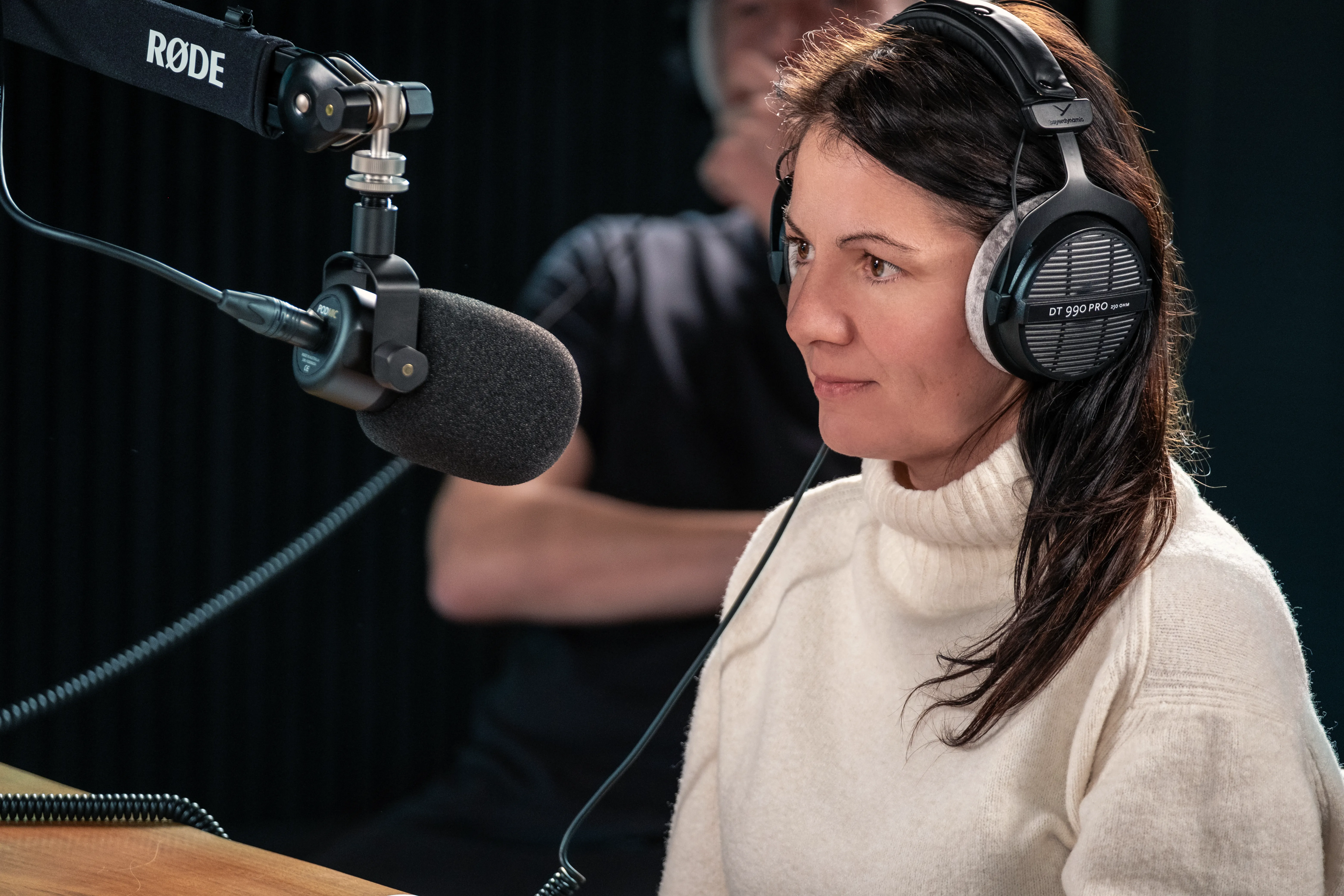 Raluca, Operations Director of Dot Performance, wearing headphones at a podcast microphone.