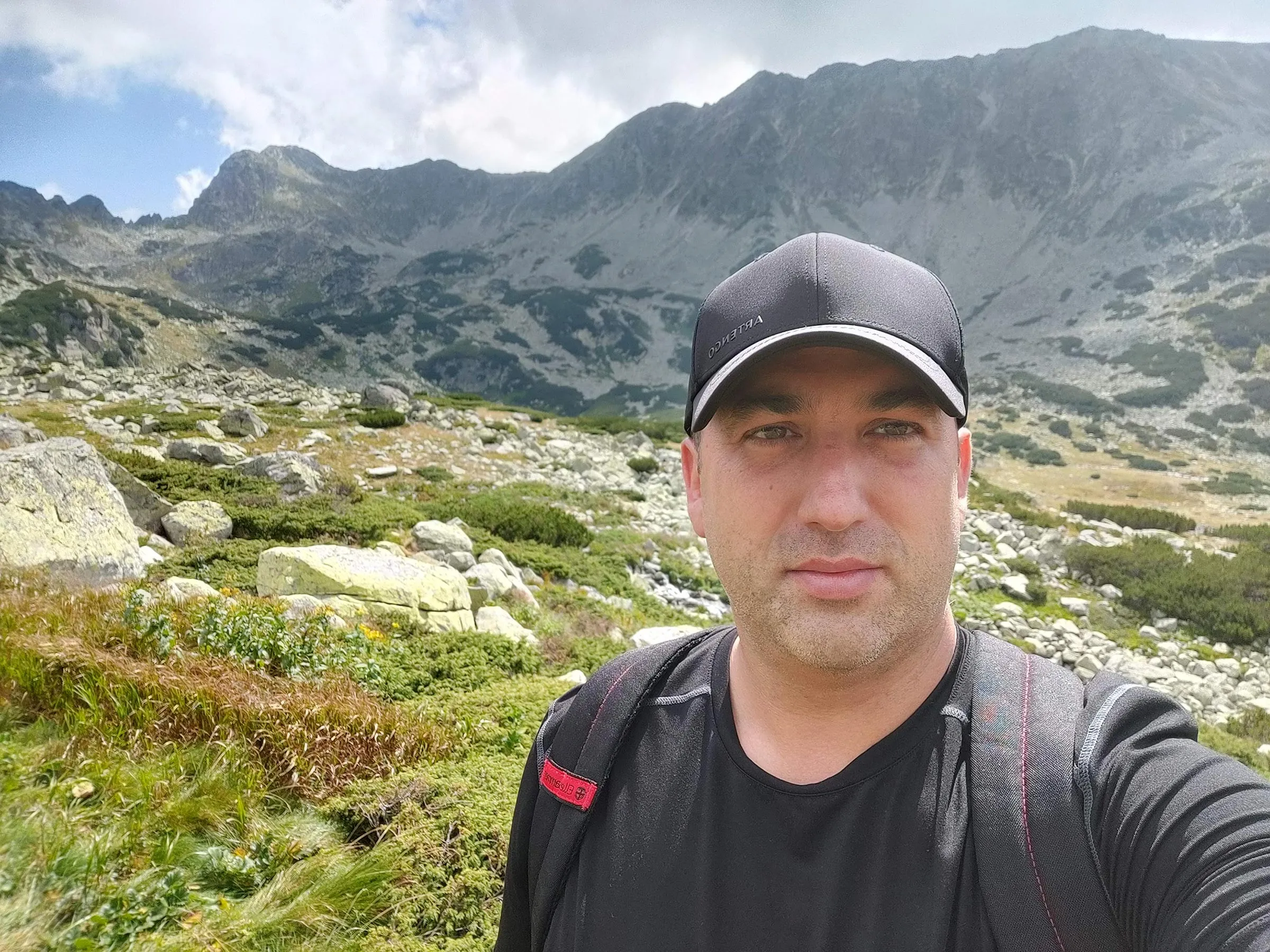 Claudiu in the mountains of eastern europe, wearing black hat and black t shirt.